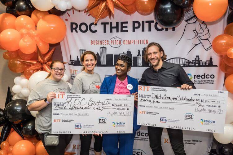 Four R I T students holding 2 ceremonial large checks.