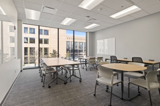a meeting space with several tables and chairs on wheels.