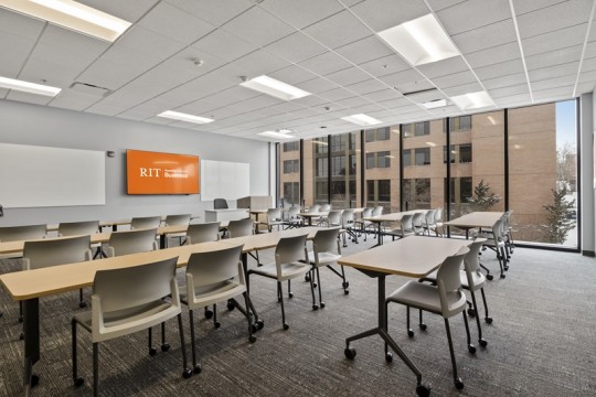 a large meeting room with long tables and chairs, and floor to ceiling, wall to wall windows.