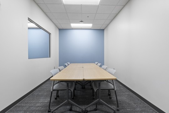 a long room with a two-way mirror, long table and eight chairs.