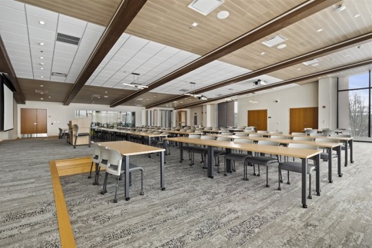 a large meeting room with long tables and chairs and a podium.