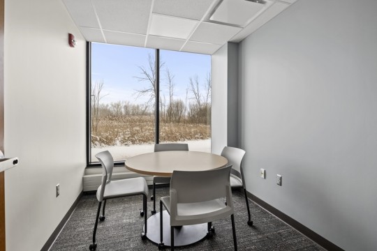 a small meeting room with a round table and four chairs.