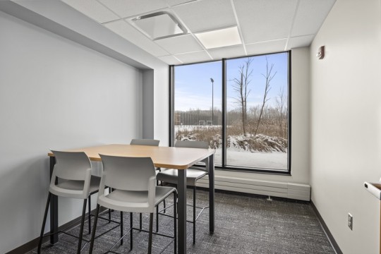 a room with a large window, and a table with four seats.