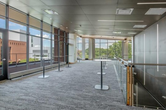 a large, carpeted reception area with high top tables.