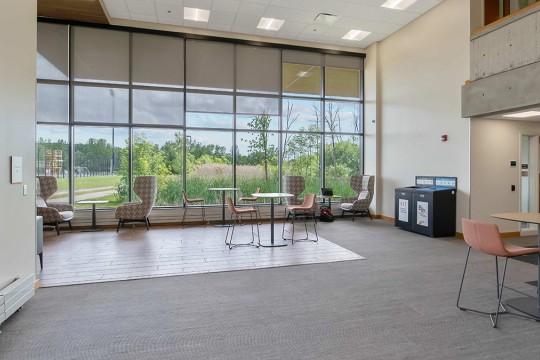 an atrium space with floor to ceiling windows and a variety of seating.