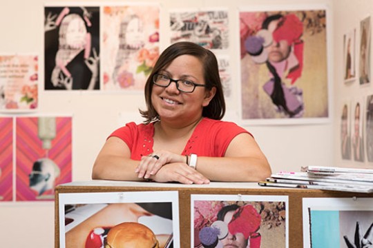 woman posing with prints of her photography.