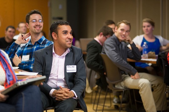 Students sitting at tables and looking toward the speaker who is off camera. 