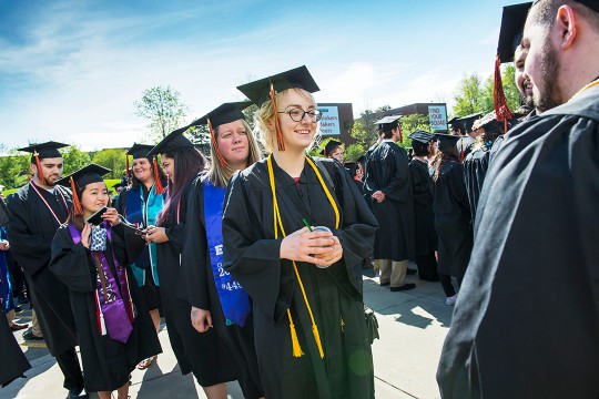 Group of students stands outside wearing black caps and gowns