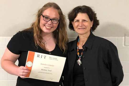 Students holds certificate standing next to Saunders College of Business dean.
