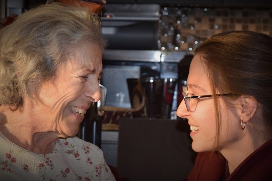 Senior citizen and young woman laugh together.
