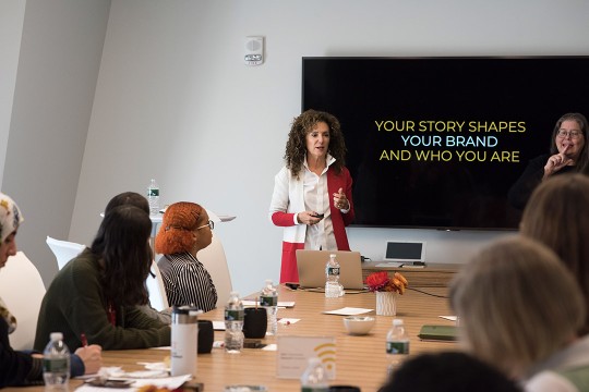 Sharon Napier stands in front of TV screen to present "Your story shapes your brand and who you are."