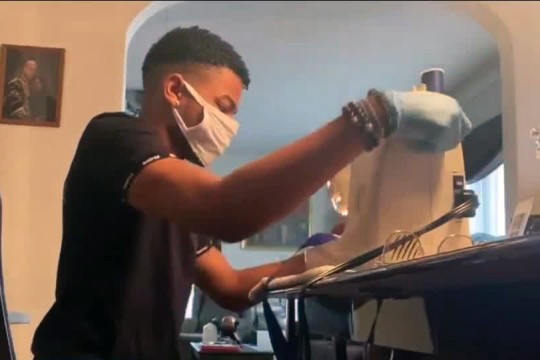 student wearing facemask and gloves operating sewing machine.
