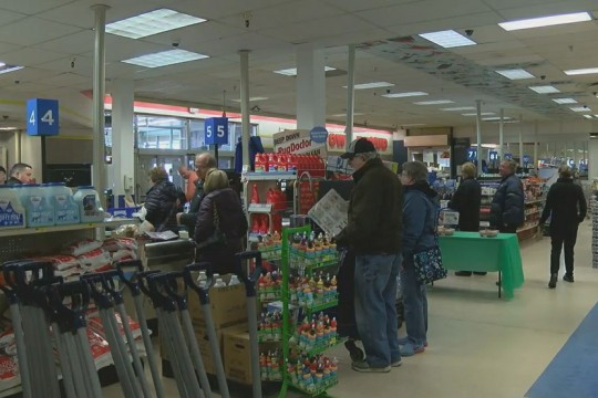 shoppers in check-out lanes at grocery store.