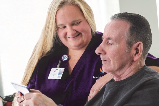 nurse helping a resident of a senior living facility use a smartphone.