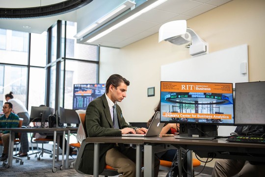 student working on laptop in business lab.
