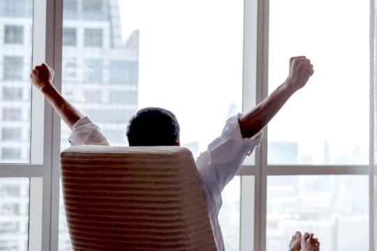 person leaning back in a chair with his arms raised in victory.