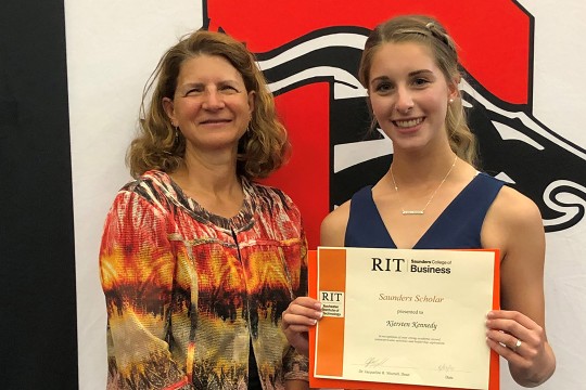 student holding certificate next to business school dean.