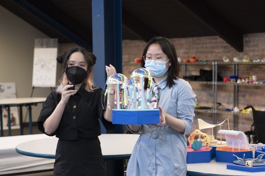 Two students hold up their game design with seascape elements