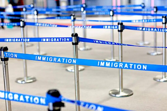 a collection of stanchions with blue ribbons in between them labeled immigration.