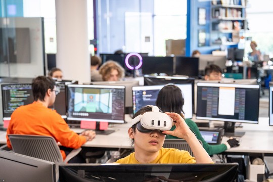 students sit and work in a game design computer lab.