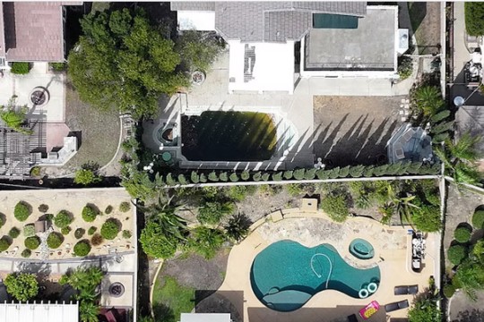 Spacious suburban homes and swimming pools are photographed from above.