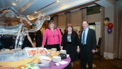 Three people posing near an ice sculpture 