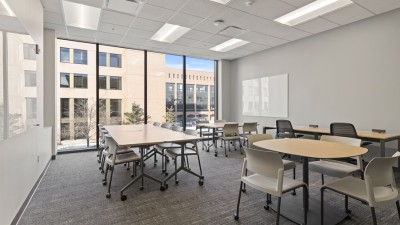 a meeting space with several tables and chairs on wheels.