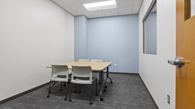 a small room with a two-way mirror, small table and four chairs.
