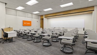 a large classroom with desks and chairs and a large whiteboard in the back.