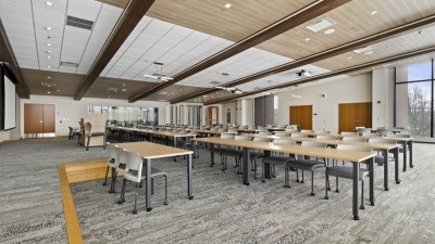 a large meeting room with long tables and chairs and a podium.