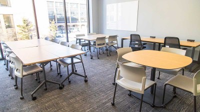 a conference room with tables and chairs, and floor to ceiling windows.