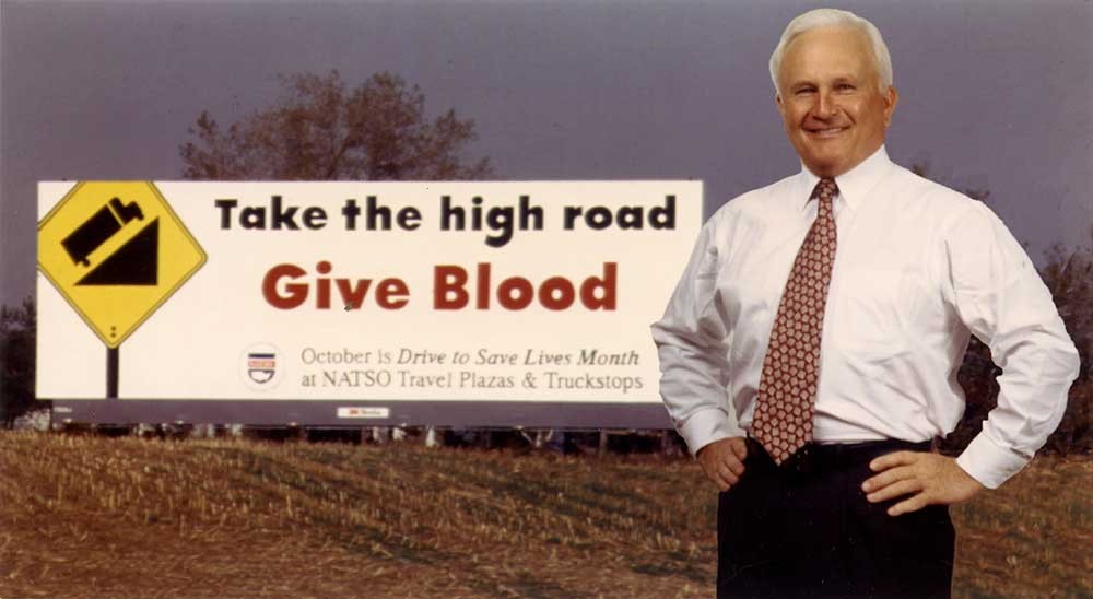 Mr. Saunders standing in front of a billboard encouraging blood donations