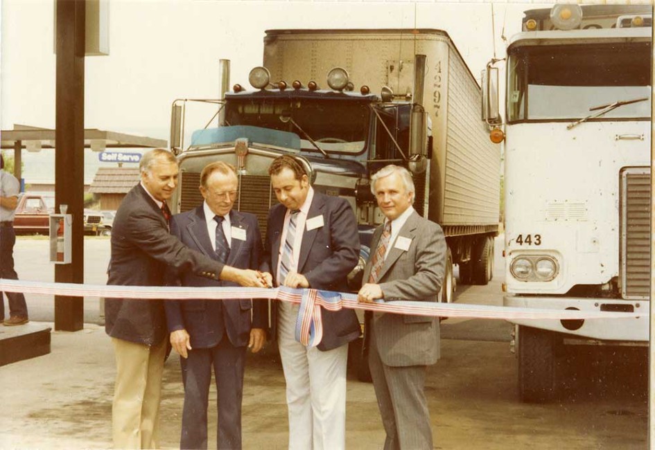 Ribbon cutting ceremony in front of large trucks