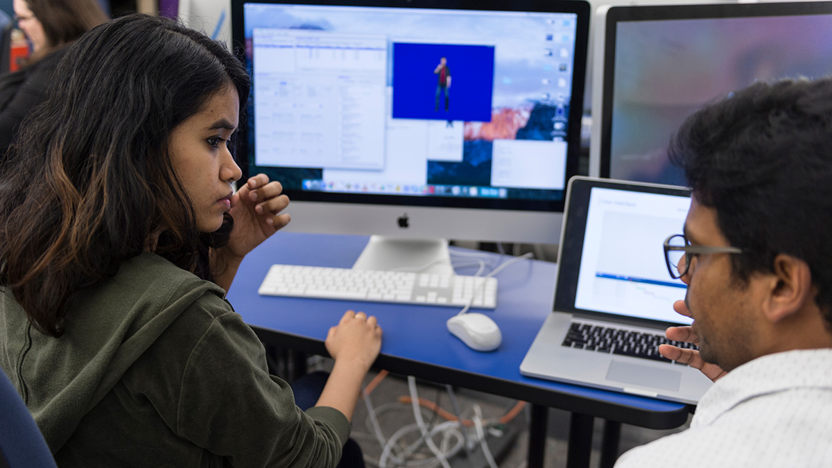 Two people interacting in front of a computer screen.