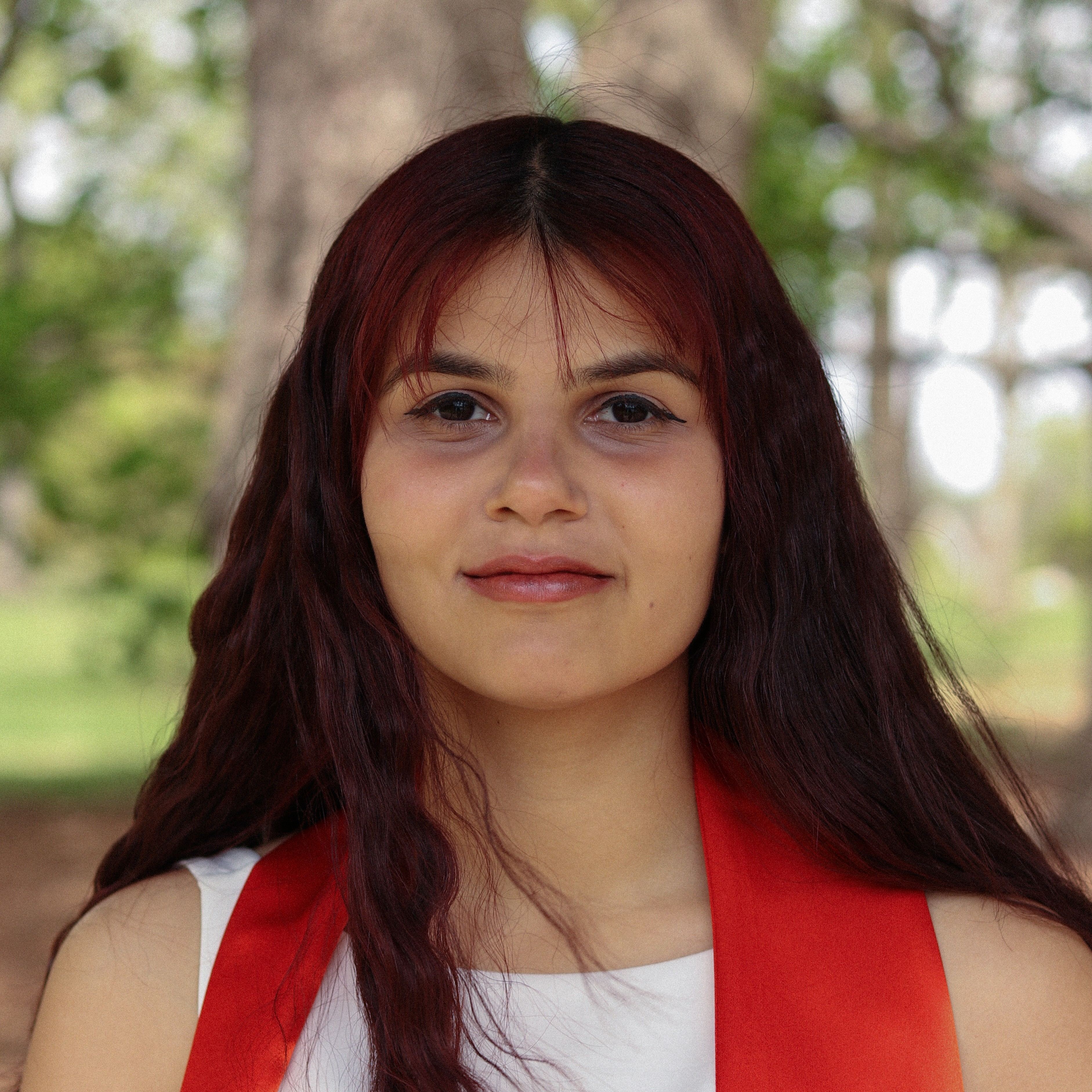 Shreya is a woman with long red hair wearing a white dress and an orange stole