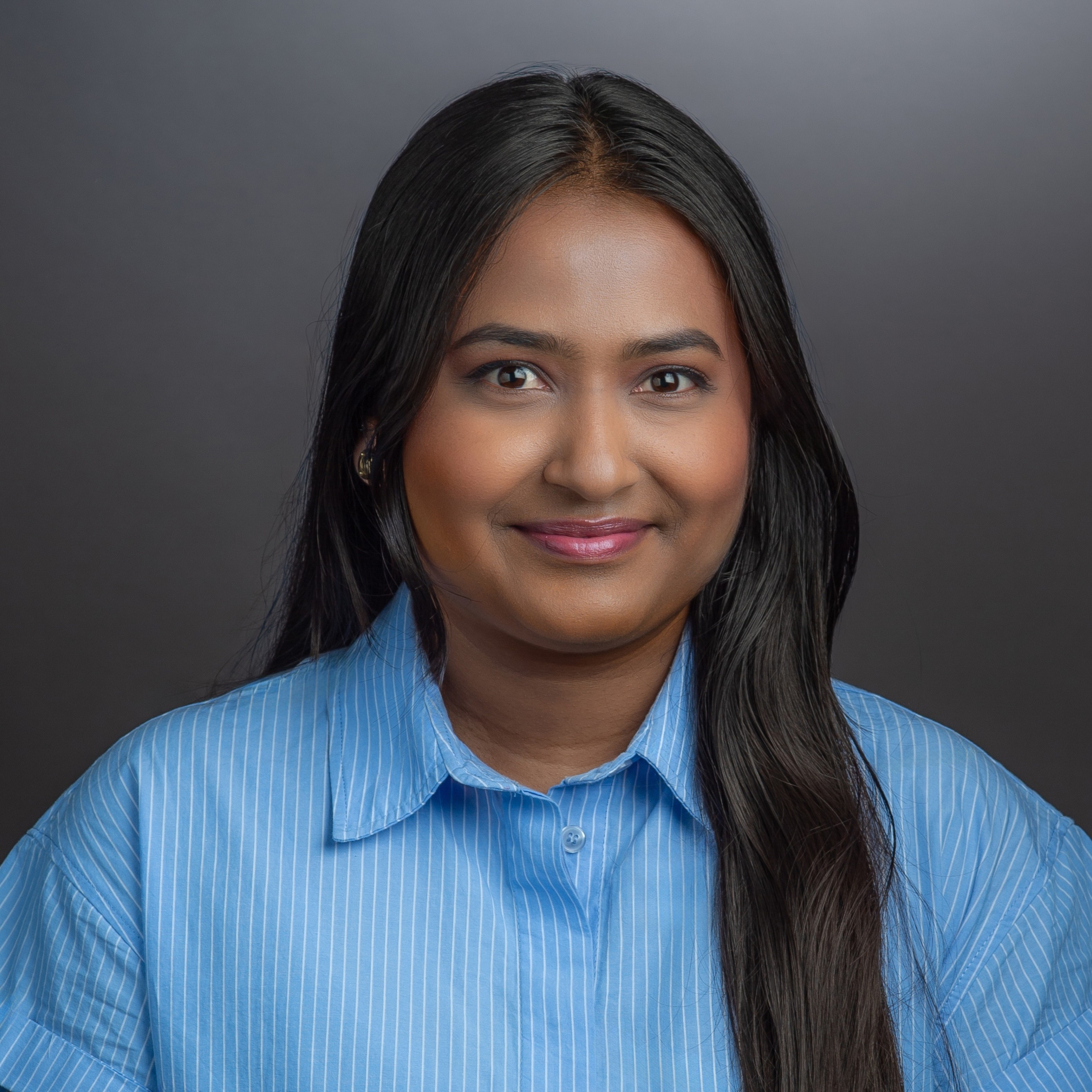 Headshot of Utkarsha Kshirsagar in a light blue shirt against a gray background.