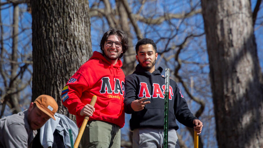 Two fraternity members standing in front of some trees during a fraternity event.