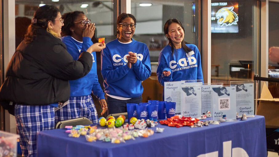 Members of the College Activities Board smiling and laughing at their booth.