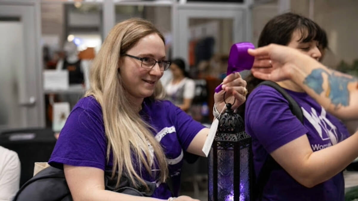 Student passing a purple ribbon to another off camera during the Lighting the Way event at TigerFest