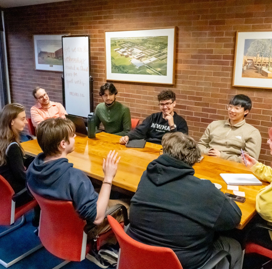 Interfaith Council meeting at a long table with students discussing 