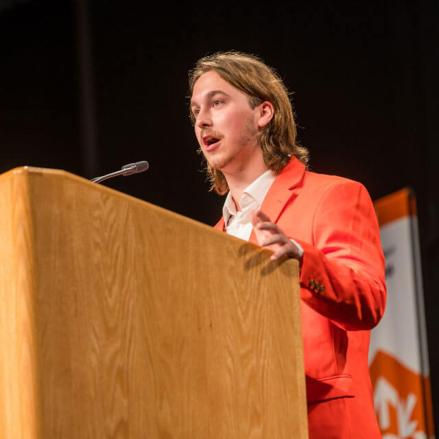 RIT Student Government President, Alex Shuron, speaking at a podium.
