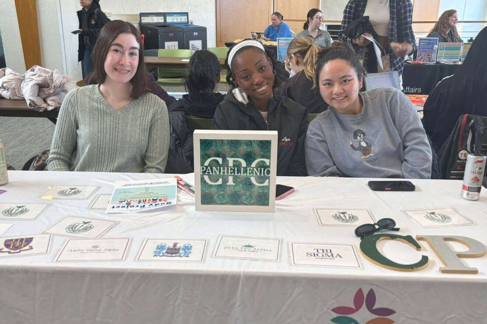 3 students smiling at a CPC booth during the Empowerment Expo