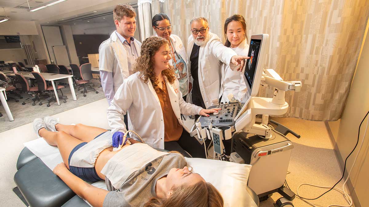 students and a professor demonstrating an ultrasound machine with a patient.