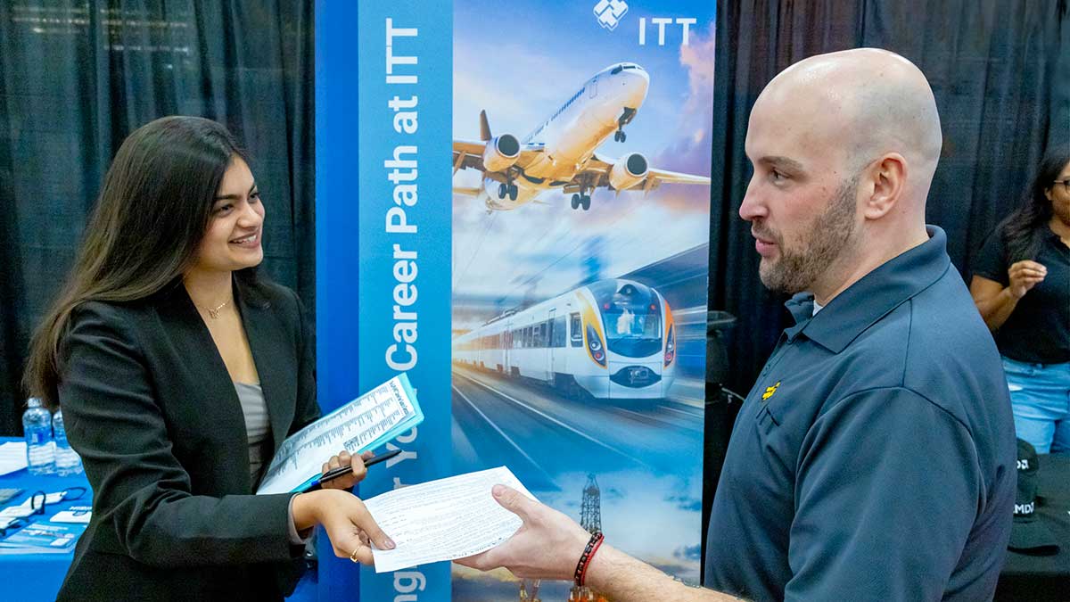 A student in business attire speaks with a recruiter at a table during the Spring Career Fair.
