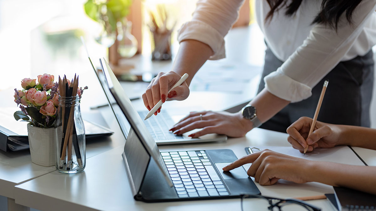 two people working with each other on two laptops.