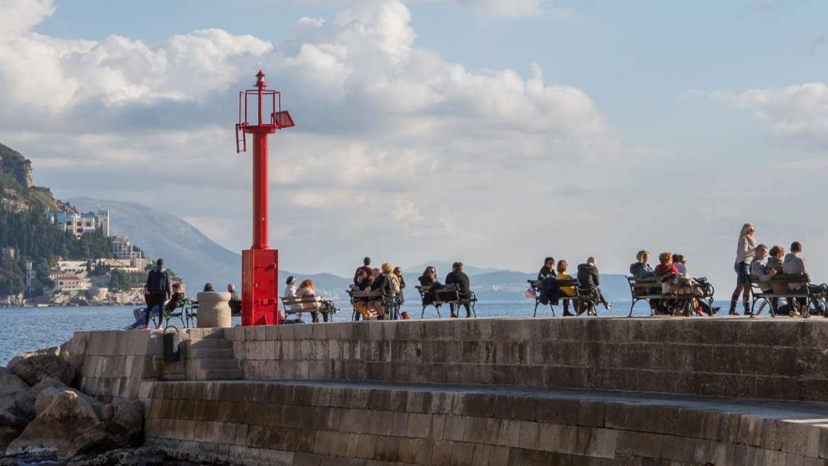 people sitting on park benches on a pier.