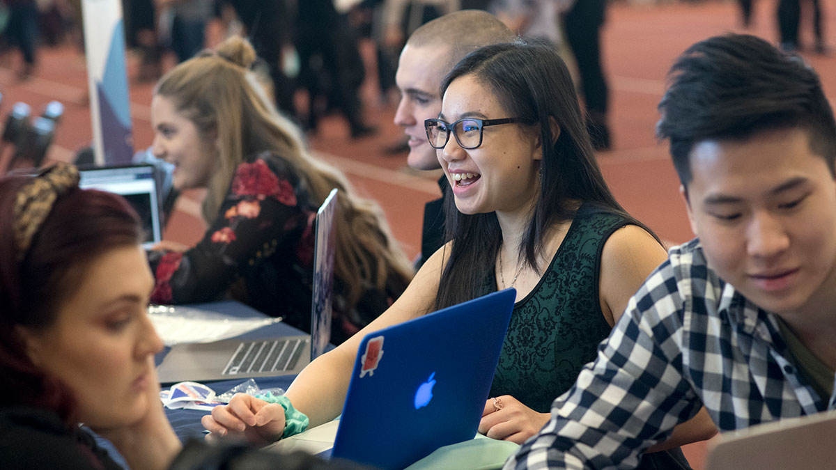 student shows portfolio work on a laptop at a career fair.