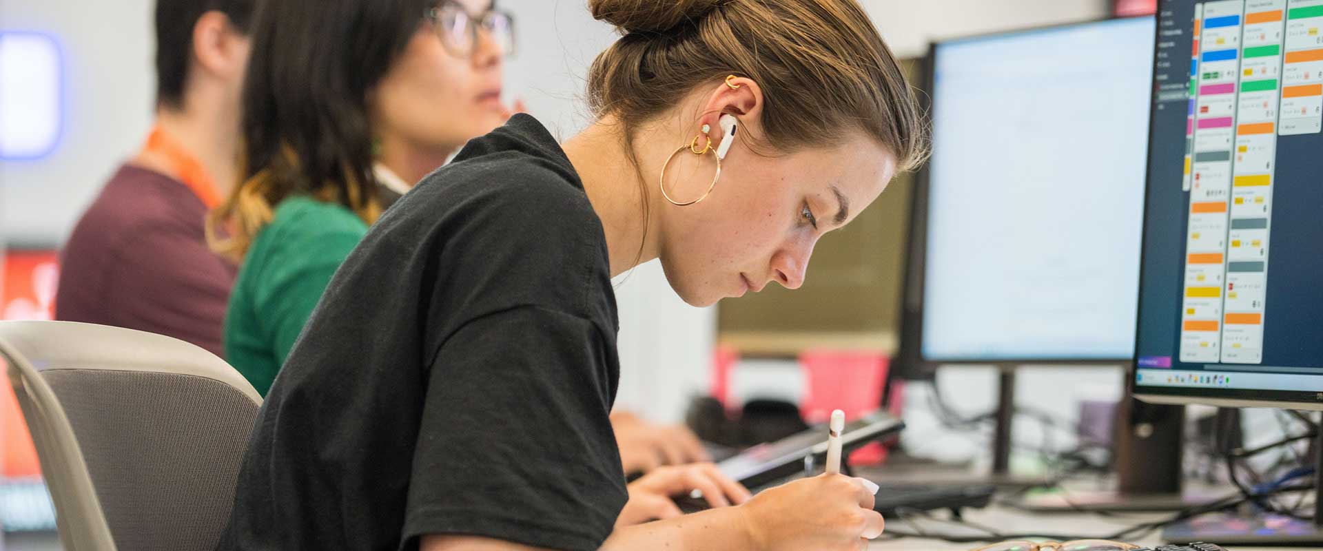 A student drawing on a digital pad with a computer screen in front of her.