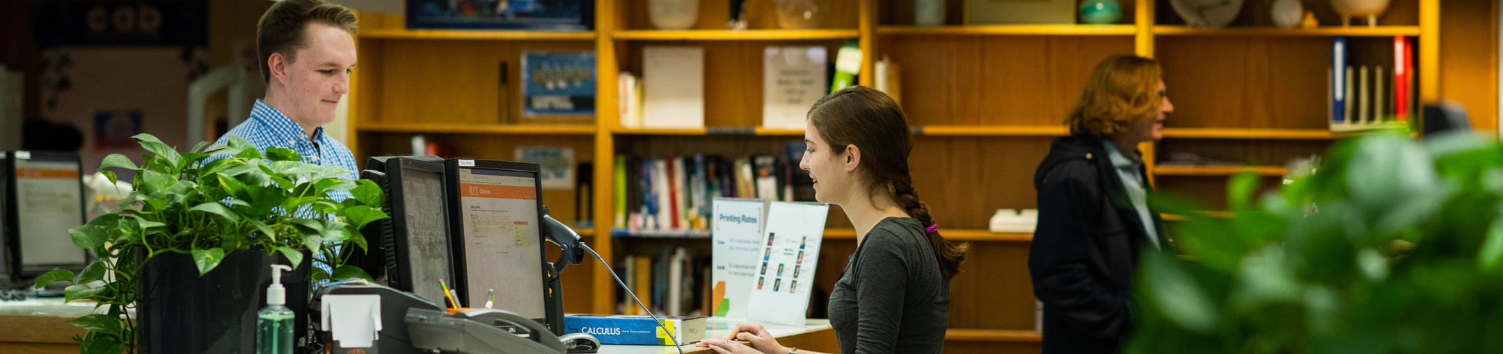 A supervisor talking to a student employee in the RIT Wallace Library.