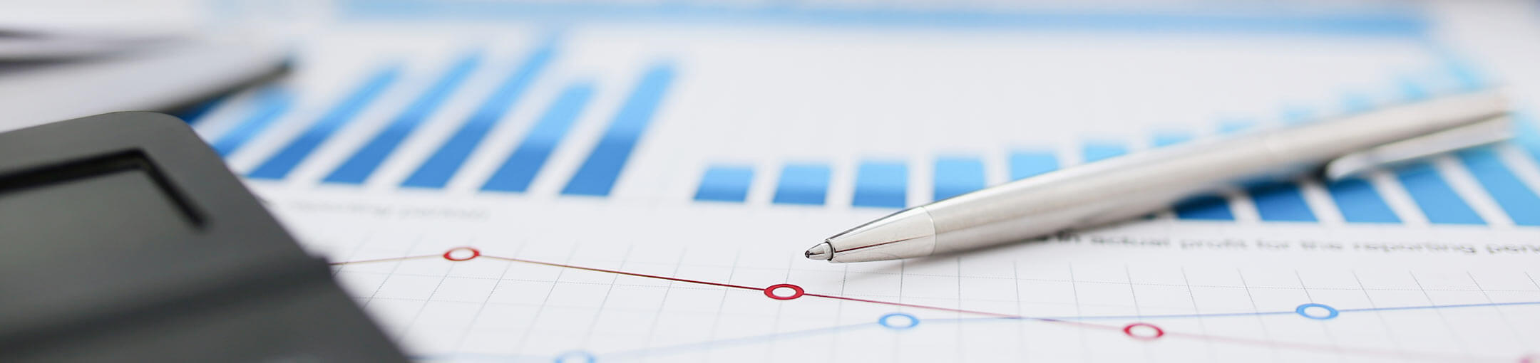 A pen and calculator laying on top of a sheet of paper with a series of graphs on it.